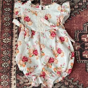 Adorable vintage style print baby onesie with floral, lace, and bow details.